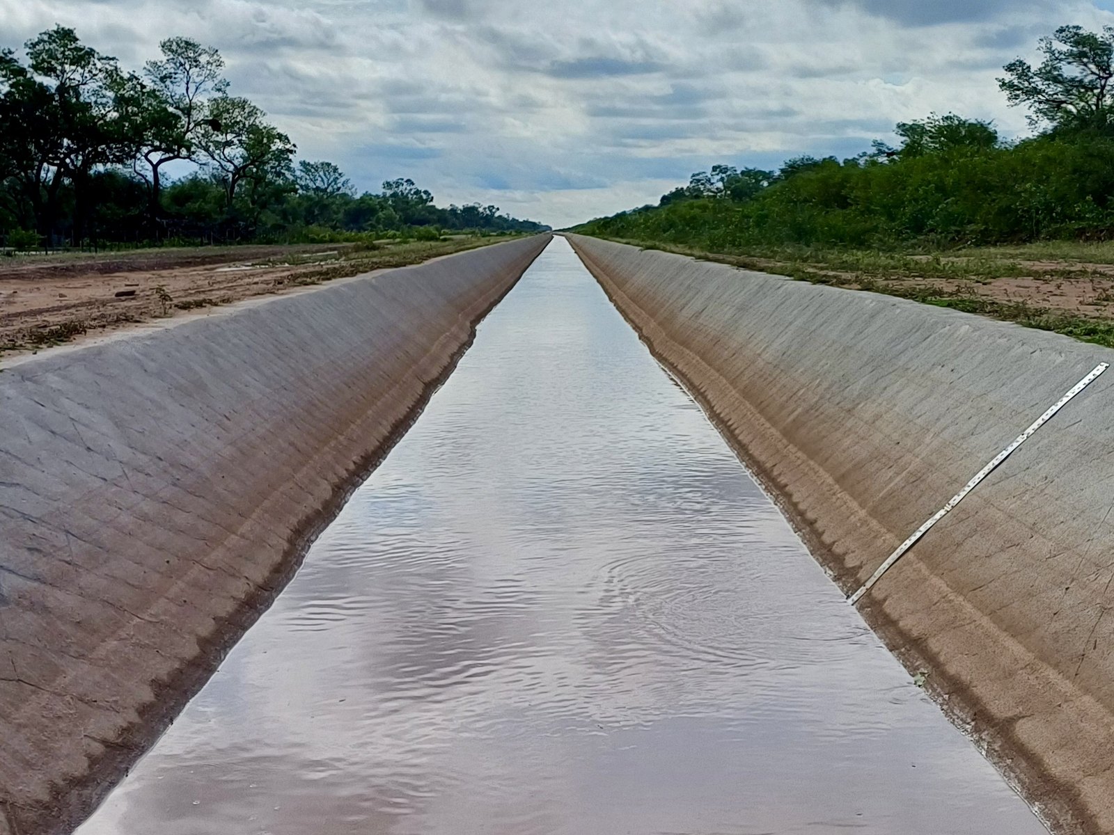 El canal de hormigón visto desde adentro, perdiéndose en línea recta hacia el horizonte